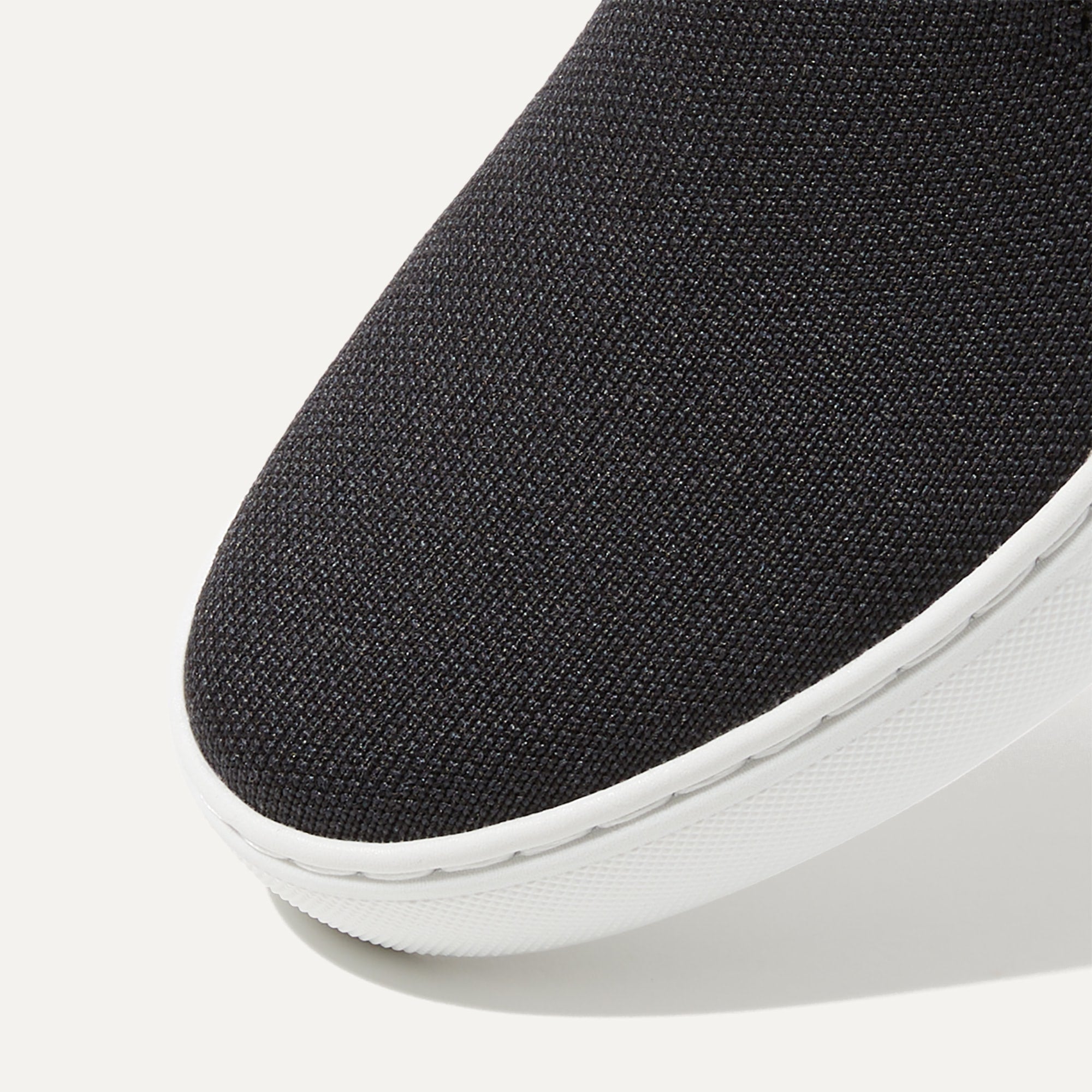 The slip-on Sneaker in Black Solid shown from the top view with detailing of the front of the shoe.