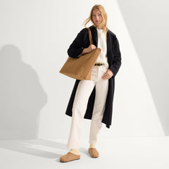 hover | Model holding The Zip Travel Tote in Hazelnut.